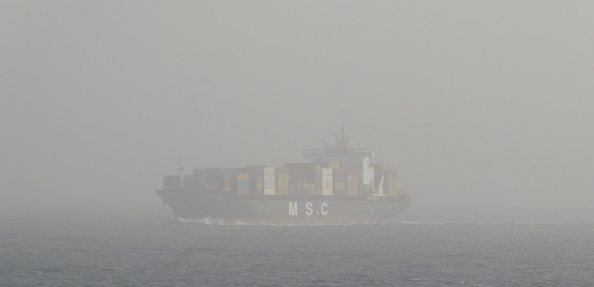 A container ship suddenly pops up from the dust-fog